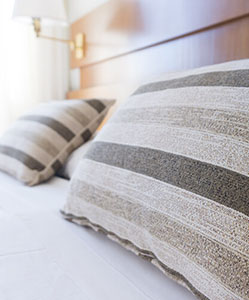 Two striped pillows resting on a neatly made bed, with soft lighting and a wooden headboard in the background.