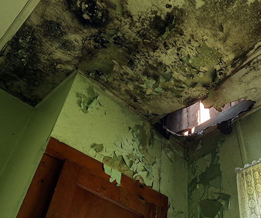 A bathroom featuring a visible hole in the ceiling, revealing the space above.